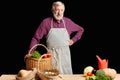 Mature farmer wants to have some rest after working day, stands near vegetables