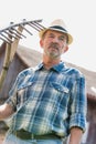 Mature farmer wearing hat while holding pitchfork at barn