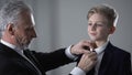 Mature father adjusting little sons tie, proud of kid, future business successor