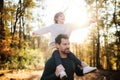 Mature father giving piggyback ride to small daughter on a walk in autumn forest. Royalty Free Stock Photo