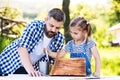 Father with a small daughter outside, making wooden birdhouse.