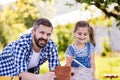 Father with a small daughter outside, painting wooden birdhouse. Royalty Free Stock Photo