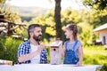 Father with a small daughter outside, painting wooden birdhouse. Royalty Free Stock Photo