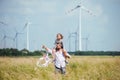 Mature father with small daughter walking on field on wind farm.