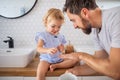 Father with small girl indoors in bathroom, painting nails.