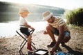 A mature father with a small toddler son outdoors fishing by a lake, talking. Royalty Free Stock Photo