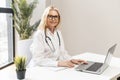 Mature female blonde doctor typing on a laptop