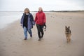 Mature female couple laughing and holding hands walking along the beach Royalty Free Stock Photo