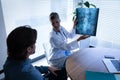 Mature female doctor showing x-ray report to patient in clinic Royalty Free Stock Photo