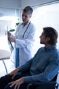 Mature female doctor showing x-ray report to patient in clinic Royalty Free Stock Photo