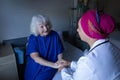 Mature female doctor talking with senior patient in hospital room Royalty Free Stock Photo