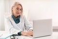 Mature female doctor working with laptop at table Royalty Free Stock Photo