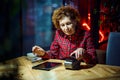 Mature female doing POS terminal and smartphone payment transaction in evening at coffee shop table. Senior customer using Royalty Free Stock Photo