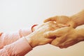 Mature female in elderly care facility gets help from hospital personnel nurse. Close up of aged wrinkled hands of senior woman. G