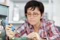 Mature female electronic engineer soldering computer Royalty Free Stock Photo