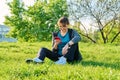 Mature female in headphones with smartphone watching video, sitting on grass Royalty Free Stock Photo