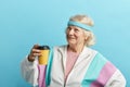 Mature female jogger in sports suit takes a rest after sport, with drink in hand Royalty Free Stock Photo