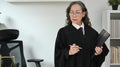 Mature female judge or lawyer or in robe gown uniform holing document and at her personal office Royalty Free Stock Photo