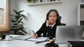 Mature female lawyer reading judiciary law document and using laptop at her office Royalty Free Stock Photo