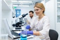 Mature female scientist in white coat at work, laboratory assistant using microscope and laptop at work, scientist Royalty Free Stock Photo