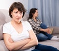 Mature female sitting at sofa after quarrel quarrel, woman on background