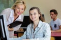 mature female teacher guiding student using computer