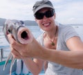 Mature female tourist smiling holding Porae fish caught on fishing charter boat in Far North District, Northland, New Zealand, NZ