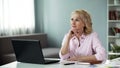 Mature female writer thinking of new series of adventure books in front laptop Royalty Free Stock Photo