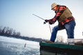 Fisherman draws hooked fish from frozen water Royalty Free Stock Photo