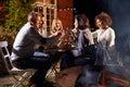 Mature Friends Enjoying Outdoor Evening Meal Around Firepit Royalty Free Stock Photo