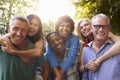 Mature Friends Giving Piggybacks In Backyard Together Royalty Free Stock Photo