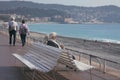 A mature, gray-haired beautiful couple: a man and a woman are sitting on a white bench on the Promenade des Anglais and looking a