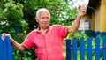 Gray haired man in red pollo swearing near fence in countryside