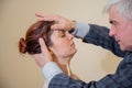 Mature gray-haired man hypnotizes Caucasian woman during hypnotherapy session. The psychologist uses alternative