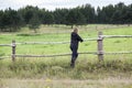 Mature grey-haired female farmer leaning on a paddock fence watching the farm field in the distance Royalty Free Stock Photo