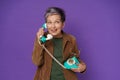 Mature grey haired woman chatting or gossiping on the phone holding retro telephone handset wearing velveteen jacket Royalty Free Stock Photo