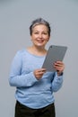 Mature grey haired woman holding digital tablet working or shopping online, checking on social media. Pretty woman in Royalty Free Stock Photo