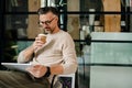 Mature grey man drinking coffee while working with tablet computer