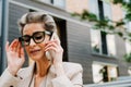 Mature grey woman in eyeglasses talking on cellphone