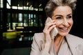 Mature grey woman laughing while talking on mobile phone