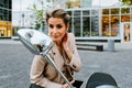 Mature grey woman smiling and looking rear-view mirror on scooter