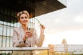 Mature grey woman smiling and using mobile phone on balcony