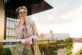 Mature grey woman smiling and using mobile phone on balcony