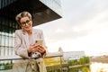 Mature grey woman smiling and using mobile phone on balcony