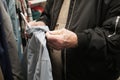 Elderly man's hands touching and feeling clothing fabric in store