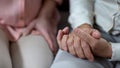 Mature hands on knees, daughter supporting father, nursing home, family love