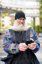 Mature handsome bearded man using phone in the city Royalty Free Stock Photo