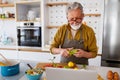 Mature handsome man cooking in home kitchen Royalty Free Stock Photo