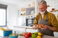 Mature handsome man cooking in home kitchen Royalty Free Stock Photo