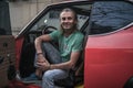 Mature handsome man sitting in red retro car and looking at camera Royalty Free Stock Photo